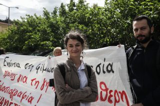 Η δημοσιογράφος Σταυρούλα Πουλημένη μπροστά σε πανό υποστήριξης